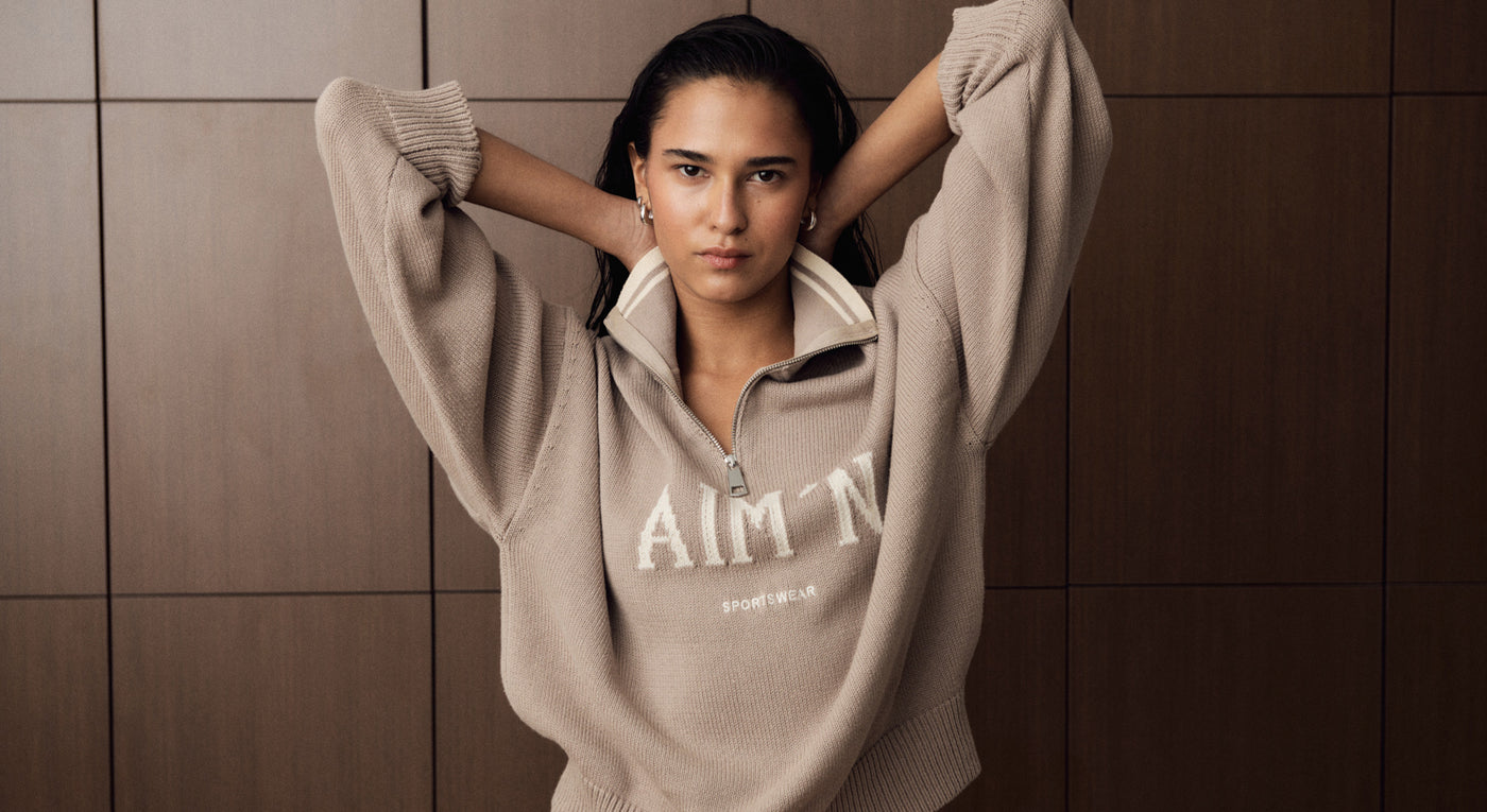 The model is wearing the Dark Clay College Knitted Half Zip.